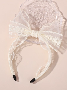 Gros plan du serre-tête nœud en dentelle crème pour enfants avec broderie florale fine