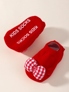 Détail de chaussettes bébé rouges avec nœud à carreaux et semelle antidérapante