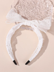 Détail du serre-tête en dentelle blanche avec nœud et embouts de confort antidérapants