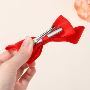 Dettaglio del fiocco in raso rosso con robusta clip a coccodrillo in metallo argento