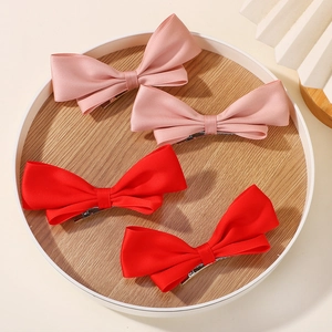Dettaglio di fiocchi per capelli in raso rosa e rossi su vassoio in legno per bambina
