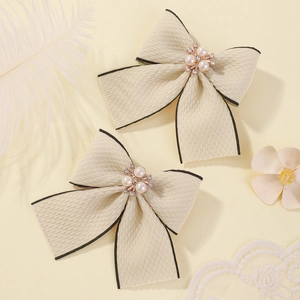 Cream fabric bow hair clip with pearl center and black stitched edges for girls