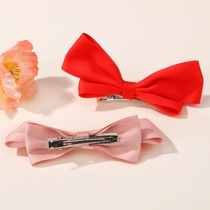 Dettaglio di fermagli per capelli a fiocco in raso rosso e rosa con clip in metallo