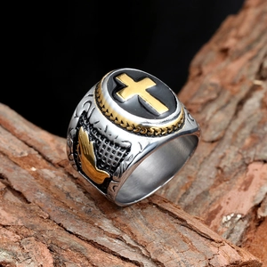 Macro shot of silver titanium ring with gold cross and praying hands relief detail