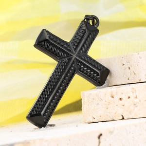 Détail macro du pendentif croix en acier inoxydable noir avec un design texturé tressé