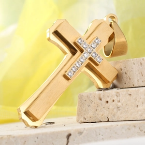 Macro shot of gold 3-layer cross pendant with cubic zirconia on textured stone base