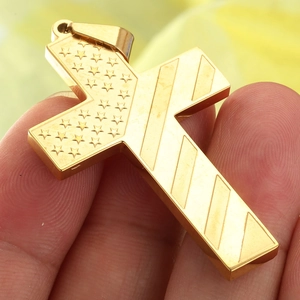 Macro detail of a golden stainless steel cross pendant with stars and stripes engraving