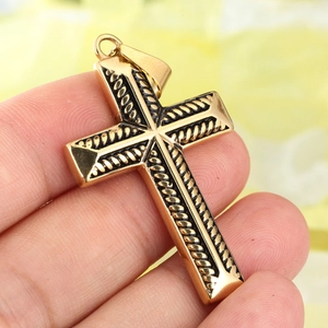 Vue détaillée d'un pendentif croix dorée avec motif de corde noire tenu à la main