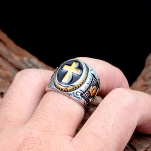Close-up of retro punk titanium steel ring with black oval and gold cross emblem
