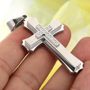 Macro detail of tiered stainless steel cross pendant with cubic zirconia inlay and brushed finish