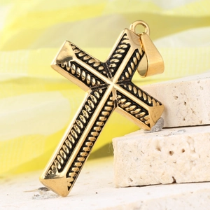 Gros plan du pendentif croix dorée avec texture de corde noire sur base en pierre