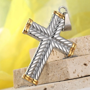 Macro shot of silver and gold stainless steel cross pendant with chevron texture detail