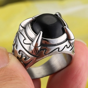 Close-up of a punk-style dragon claw ring featuring a black oval stone and gothic carvings