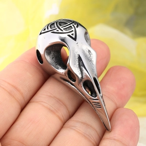 Detail of vintage silver Viking crow skull pendant with intricate Celtic knot engraving