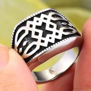Détail des motifs complexes gravés sur une bague pour homme en métal argenté avec patine