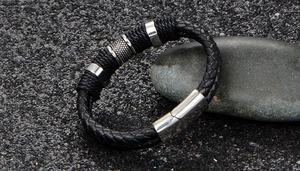 Detalle de pulsera de cuero trenzado negro multicapa con cierre magnético de acero pulido