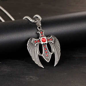 Macro detail of gothic angel wing cross pendant with red crystals on pearl chain