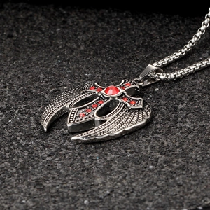 Macro detail of vintage stainless steel eagle wing cross pendant with red gemstones