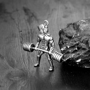 Détail macro d'un pendentif de fitness poli montrant une figure musclée soulevant une barre