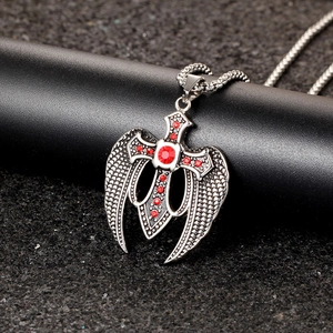 Detailed view of vintage stainless steel cross wing pendant with red crystal inlay