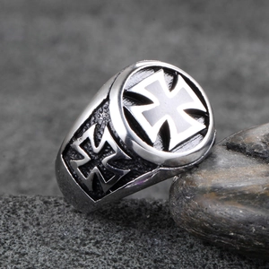 Macro shot of retro stainless steel ring with black iron cross pattern on dark stone