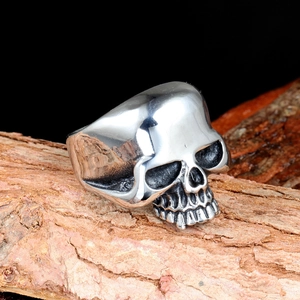 Polished punk skull ring made of stainless steel displayed on a rustic wood background