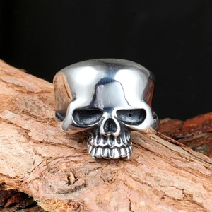 Punk style skull ring for men in polished stainless steel on a natural wood background
