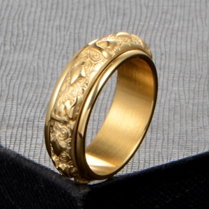 Detailed macro view of golden stainless steel ring with embossed patterns and brushed finish