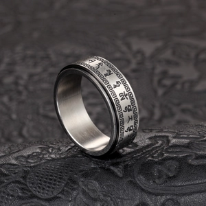 Détail de la bague rotative avec gravure de mantra bouddhiste sur surface en acier brossé
