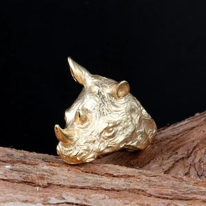 Golden rhinoceros head ring in stainless steel with detailed animal skin texture on wood