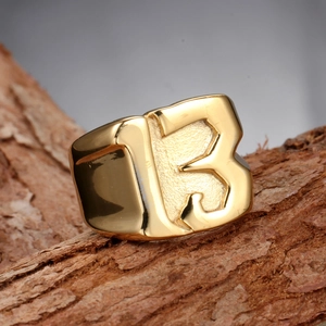 Polished gold men's titanium ring with number 13 on textured wood background