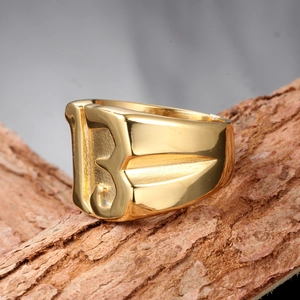 Macro shot of gold-plated wide ring featuring a bold letter B on natural wood texture