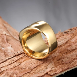 Polished gold titanium steel men's band ring displayed on natural wood grain surface
