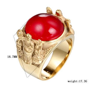 Detail of vintage gold titanium steel ring with red gemstone and embossed figures