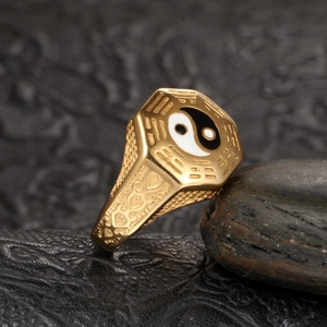 Macro shot of gold Taoist Tai Chi Bagua signet ring on textured dark stone surface