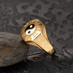 Macro detail of men's stainless steel Bagua ring with gold finish and black enamel