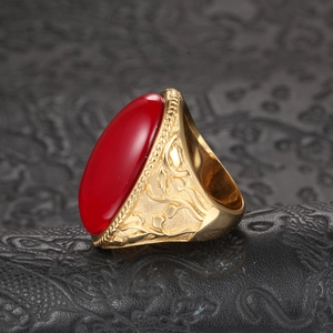 Macro side view of vintage men's gold plated ring with large oval red gemstone and floral relief
