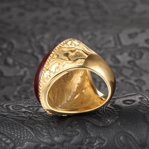 Macro detail of a vintage gold titanium ring with red gemstone and floral vine carvings