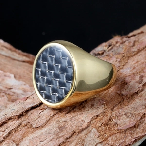 Macro shot of gold stainless steel ring featuring a black carbon fiber round inlay detail