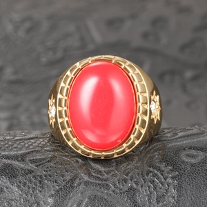 Détail d'une pierre précieuse rouge sur bague dorée avec accents d'étoiles brillants