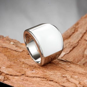 Bague large en métal argenté poli avec incrustation carrée blanche sur fond de bois texturé