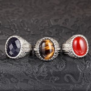 Detalle de anillos de plata con piedras de lluvia azul, ojo de tigre y ágata roja