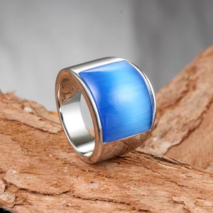 Détail de bague en titane argenté avec pierre oeil de chat bleue sur décor en bois