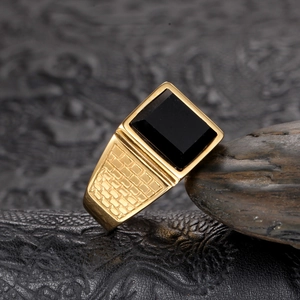 Détail macro d'une bague chevalière dorée pour homme avec pierre noire et gravures