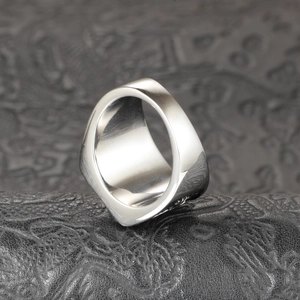 Detailed close-up of a wide polished stainless steel ring on a black textured surface