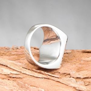 Anillo punk de acero de titanio pulido sobre fondo de corteza de madera natural