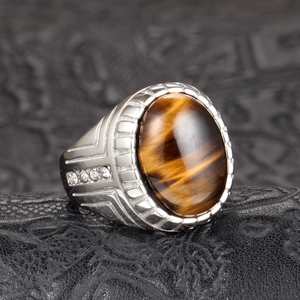 Detalle de anillo para hombre en acero con piedra ojo de tigre ovalada y circonitas laterales