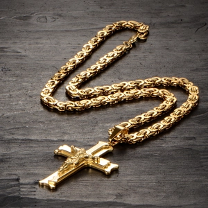 Detail of gold crucifix pendant on Byzantine chain over rustic dark wood surface