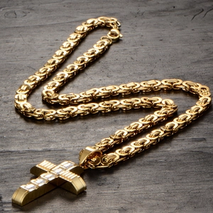 Close-up of golden stainless steel Byzantine chain with geometric cross pendant