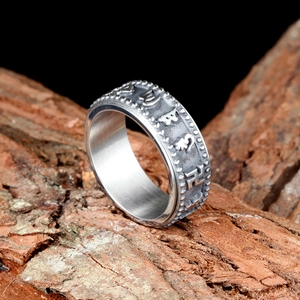 Bague rotative mantra bouddhiste en acier inoxydable argenté sur fond bois naturel